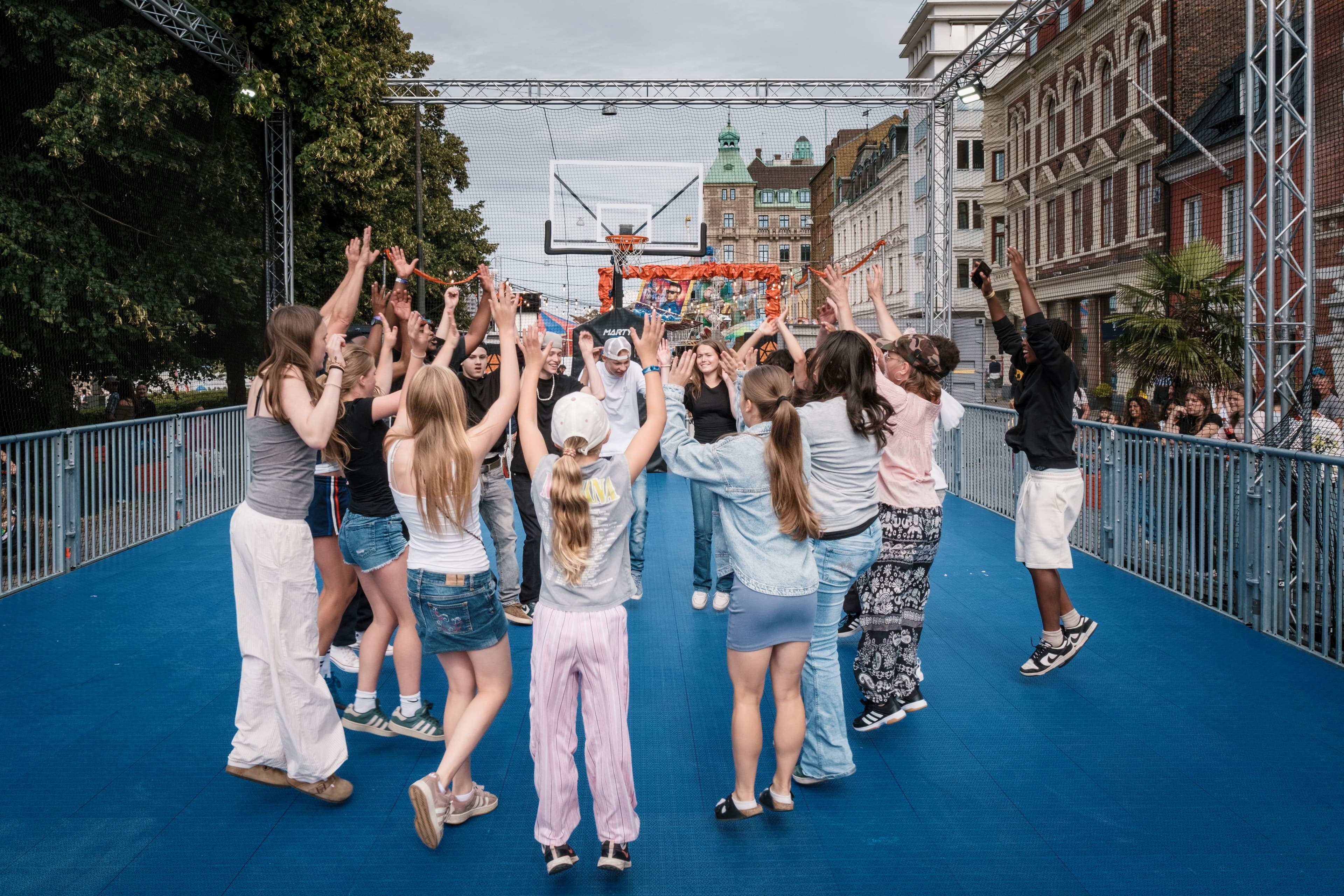På Ungdomsområdet på Malmöfestivalen står många ungdomar i en ring med händerna upp i luften.