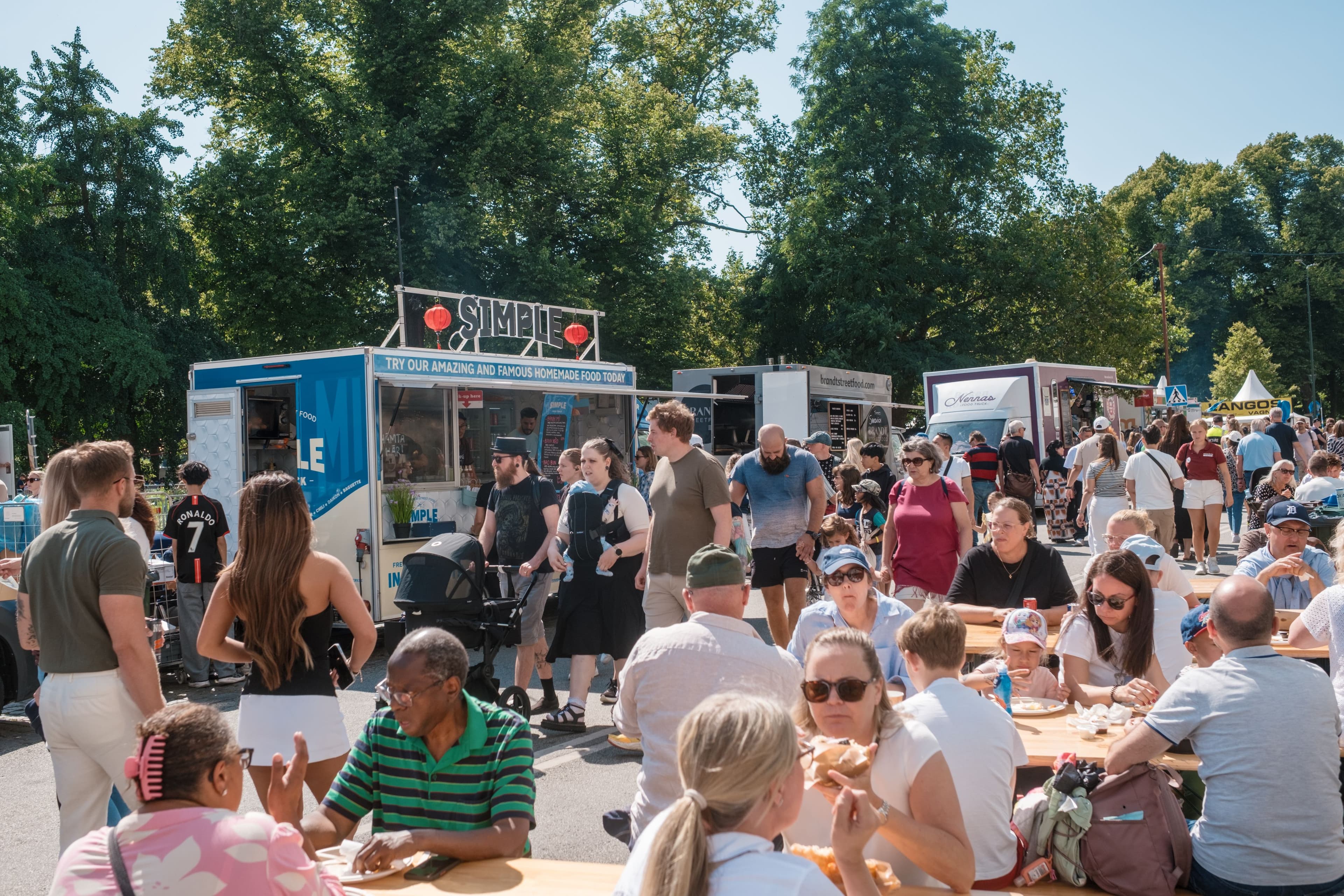Mycket folk som sitter ner och äter eller rör sig på matområdet på Malmöfestivalen.